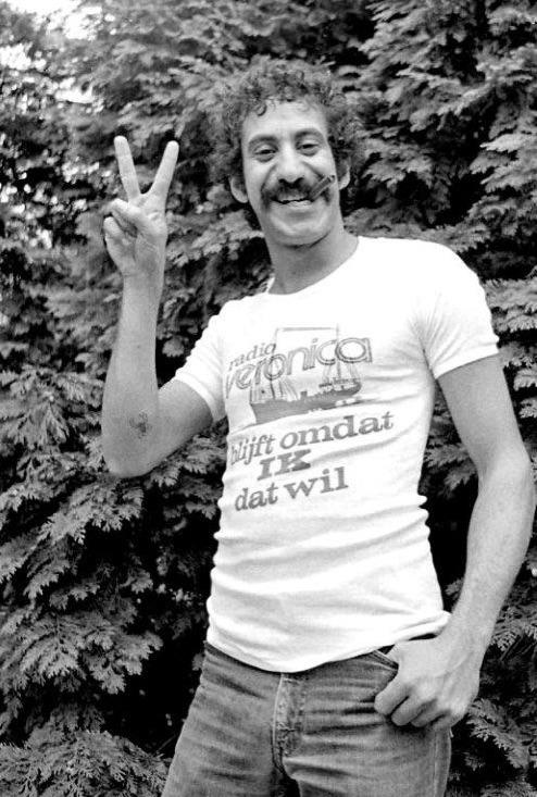 a man standing in front of a bush making the peace sign