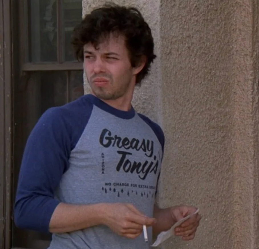 a man standing next to a building holding a cigarette