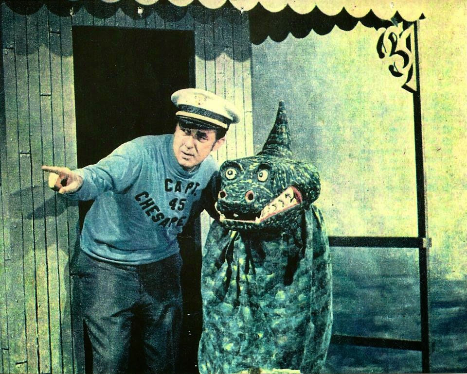 a man standing next to a fake alligator