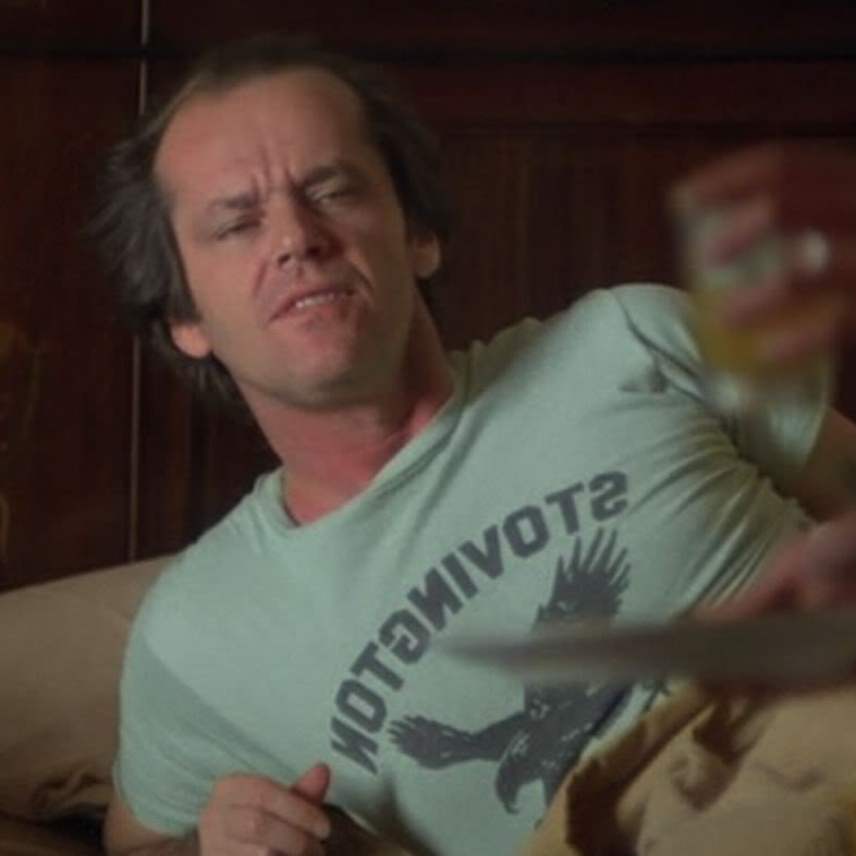 a man sitting on a bed holding a glass of wine