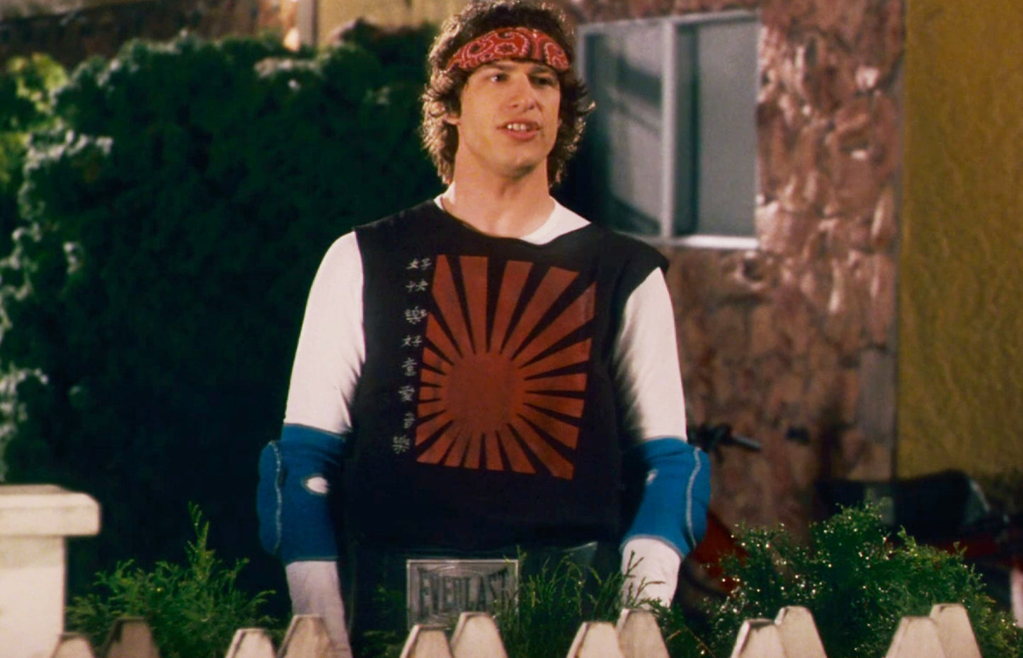 a man wearing a bandana standing in front of a fence