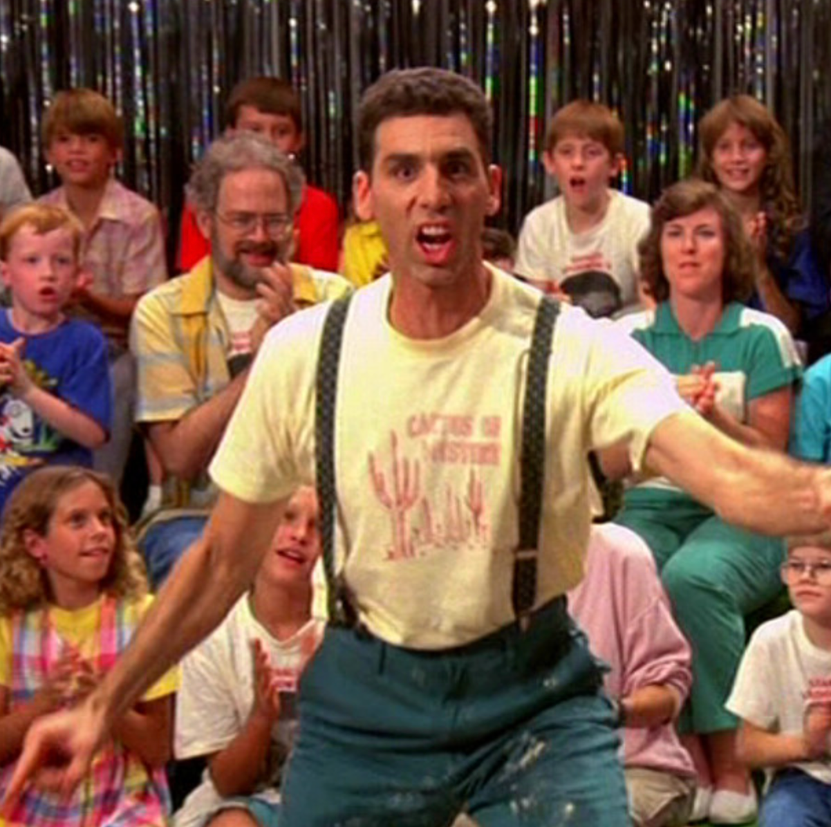 a man with suspenders and suspenders is dancing in front of a group of