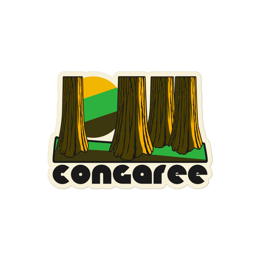 A retro kiss cut sticker that says Congaree underneath the image of multiple trees and a yellow/green/brown sun above a green and brown striped ground, referencing Congaree National Park in South Carolina.