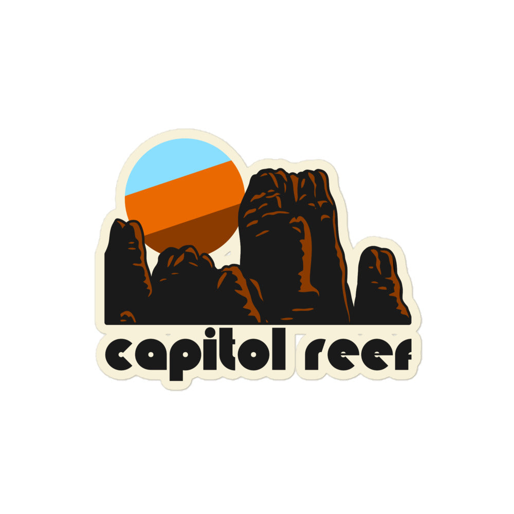 A retro Capitol Reef kiss cut sticker with the image of a stunning red rock landscape reminiscent of America's southwest and a blue/orange sun setting in the distance, referencing Capitol Reef National Park in Utah.