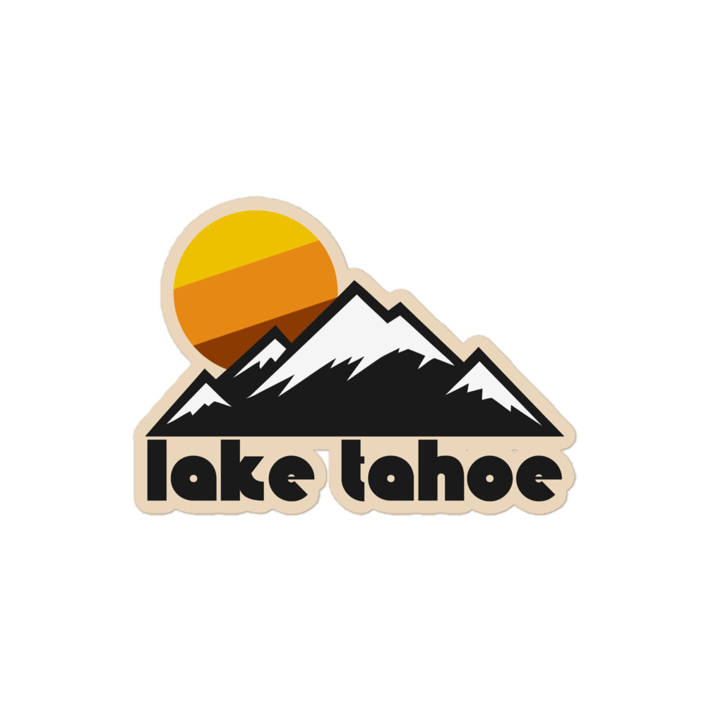 A retro kiss cut sticker that says "Lake Tahoe" with a beautiful mountain range, the peaks covered in snow, and a setting yellow, orange, and brown sun in the background.