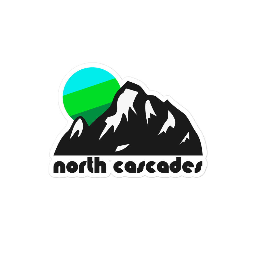 A North Cascades vintage kiss cut sticker with the image of a large mountain with crevices filled with snow and a blue and green sun setting. References North Cascades National Park in Washington State near Seattle.