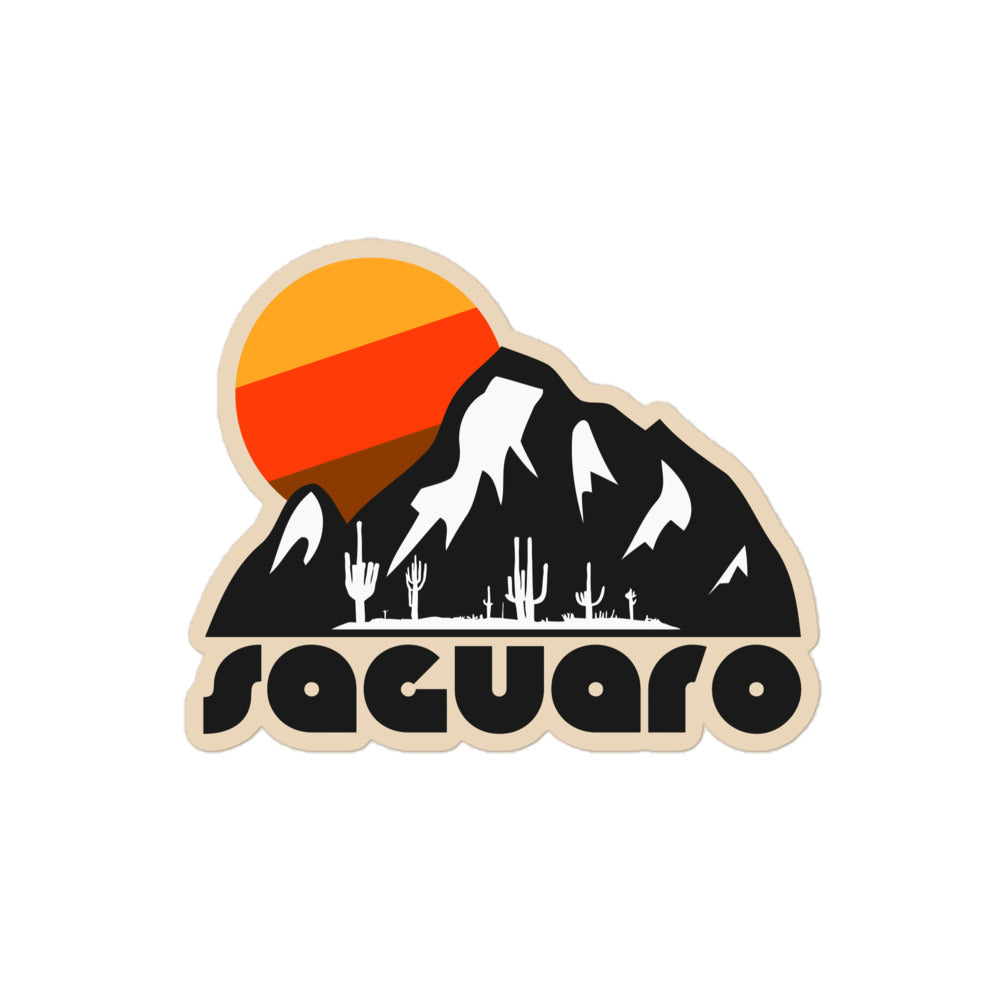 A retro kiss cut sticker that says "saguaro" underneath an aesthetic mountain landscape with a desert and cacti under a setting yellow, orange, and brown sun. References Saugaro National Park in Arizona, known for having the largest cacti in the US.
