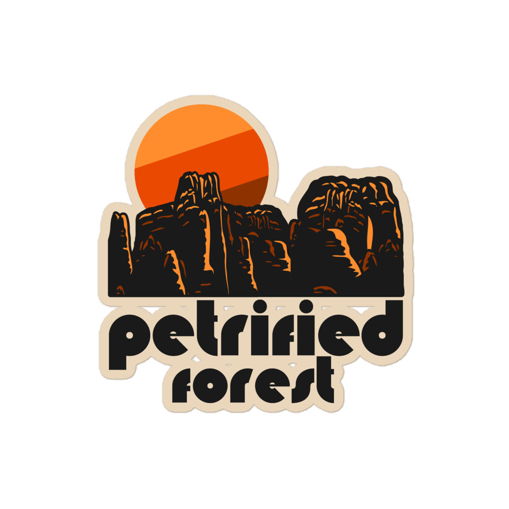 A retro kiss cut sticker that says "Petrified Forest" under the image of a red rock landscape with a red, orange, and brown sun, in reference to Petrified Forest National Park in Arizona.
