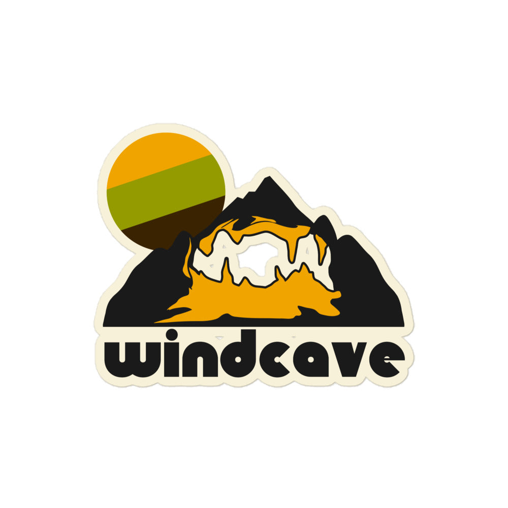A white kiss cut retro sticker that says "Windcave" referencing Wind Cave hiking trail, one of the most complex caves in the entire world. Image of a mountain and a hiking trail within and a tricolored sun in yellow, green, and brown.