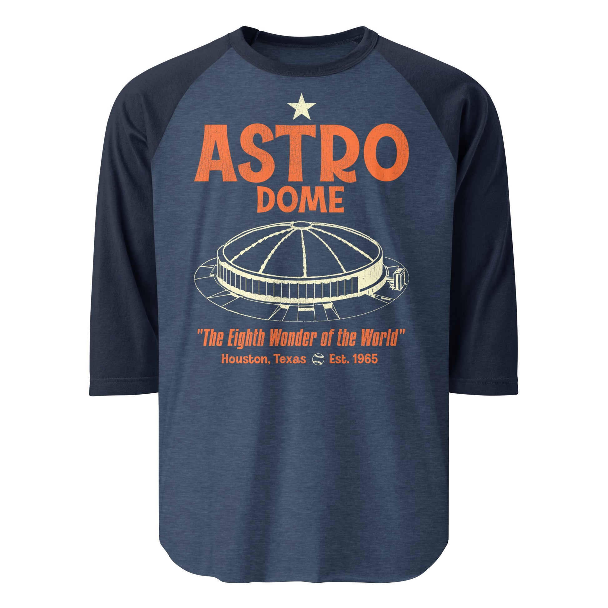 A heather and navy blue vintage 3/4 sleeve raglan style shirt that says "Astro Dome" from "Houston, Texas" which was established in 1965 as the first domed stadium in the world. Coined as "The Eighth Wonder of the World" by Judge Roy Hofheinz. Shirt has the image of the circular baseball stadium with a domed ceiling and a small baseball which served the Houston Astros MLB team and the Houston Oilers NFL team.