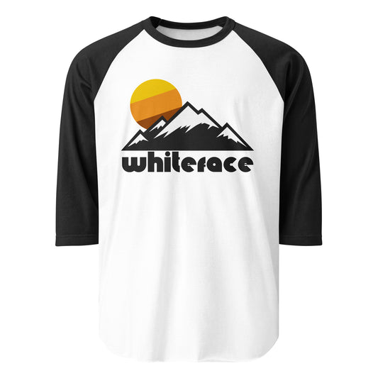 A three quarter sleeve raglan style white and black colored shirt that says 'Whiteface' in reference to Wilmington, New York's Whiteface Mountain, known as one of the High Peaks of the Adirondack Mountain Range and as the location of the alpine skiing competitions in the 1980s Olympic Winter Games. The shirt includes the image of multiple snowcapped mountains and a tricolored sun setting over the landscape.