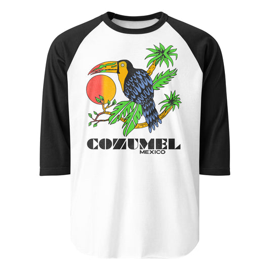 A vintage raglan style three quarter sleeve black and white tourist shirt that says Cozumel Mexico, referring to the popular cruise ship destination in the Yucatán Peninsula. Image of tropical bird sitting on brown palm tree branches with green leaves. Hombre orange and red sun is in the back.