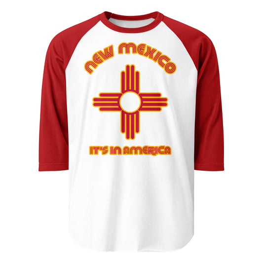 A 70s style 3/4 sleeve raglan red and white shirt that says "New Mexico" and "it's in America" with an image of the US state's flag in red and yellow, symbolizing the Zia tribe's sacred sun symbol.