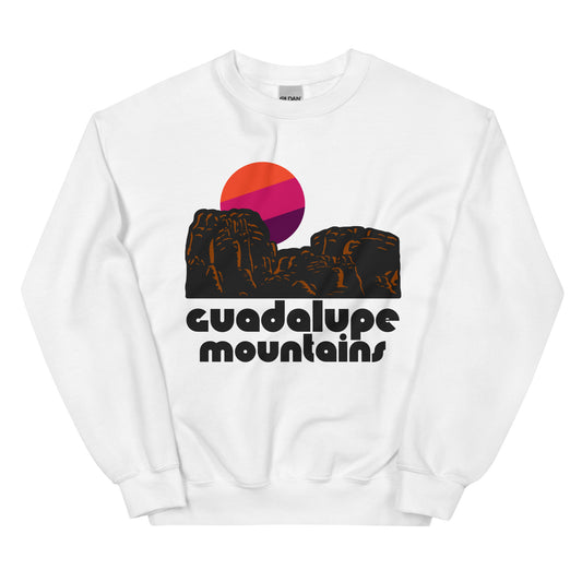 A retro 80s style crew cut white sweatshirt that says "Guadalupe Mountains, the national park in texas, with a mountainous red brown rocks in desert landscape and a setting sun image.