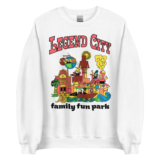 A 70s style tourist crew neck white sweatshirt that says "Legend City", "family fun park" in reference to the now closed theme park close to Pheonix and Tempe, Arizona. Images of people on amusement park rides including trains, boats, & skyway gondolas. Images of pink, orange, and red buildings, blue and green swirling waves, and a fake cannon saying "boom".