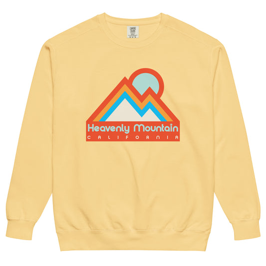A butter yellow colored retro Heavenly Mountain, Califronia crew neck sweatshirt. Includes image of mountain landscape in dark orange, light orange, and bright blue, along with a circular sun setting behind the peaks in ice blue color. Sweatshirt references Heavenly Mountain Ski Resort on the shres of Lake Tahoe in the Sierra Nevadas.
