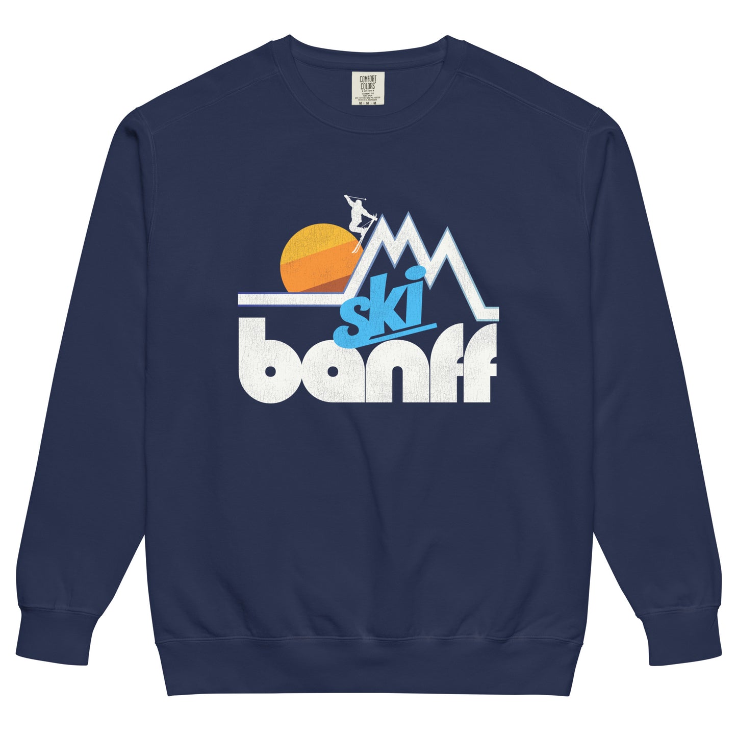 A navy blue vintage Ski Banff crew neck sweatshirt with the image of a mountain landscape and a skier jumping in front of a beautiful sun, in reference to Banff National Park in Canada's Alberta Rocky Mountains, known for its ski slopes.
