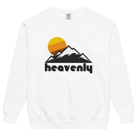 A white crew neck souvenir sweatshirt that says Heavenly and includes an aesthetic mountain range and sun graphic, representing the Sierra Nevada Mountain Range where Heavenly Ski Resort sits. The ski and snowboarding destination is famous as the highest resort near Lake Tahoe, with almost 5,000 acres of skiable terrain and trails of all levels.