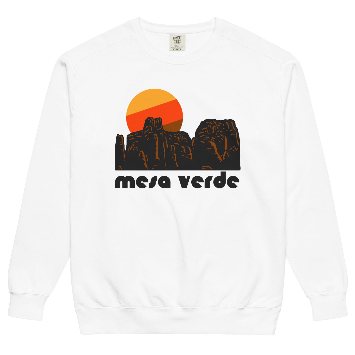 A vintage, 80s style white crew neck sweatshirt that says 'mesa verde' in reference to Mesa Verde National Park in Colorado, known for its cliff dwellings and mesa top sites of the Ancestral Pueblo peoples and culture. The sweatshirt includes an image of a red, granite, rocky landscape and a setting yellow, red, and brown sun.