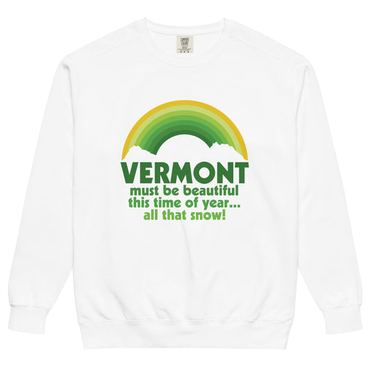 A vintage, 80s style tourist white colored crew neck sweatshirt that says "Vermont must be beautiful this time of year... all that snow!" in various shades of green, referencing the 1954 musical comedy film "White Christmas". Image of a green and gold rainbow above the words, and two white clouds.