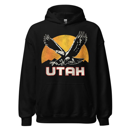 A black colored retro 80s style Utah hoodie sweatshirt. Image of an eagle, in reference to Utah's state bird of prey, flying over a mountain range landscape with a large moon behind.