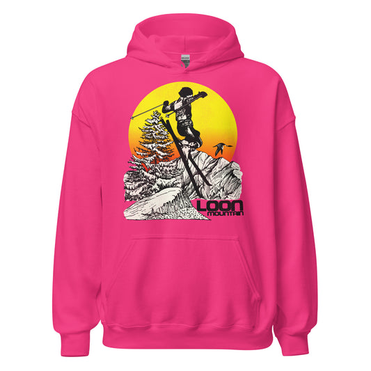 A bright pink heliconia travel hoodie sweatshirt with the text "Loon Mountain", the ski and snowboard resort in the White Mountain Range in New England. Image of skiier flying past beautiful snow covered mountains, a loon bird, a tree, and a bright yellow and orange sunset.