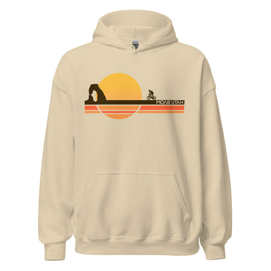 A comfy vintage sand colored hooded sweatshirt that says "Moab, Utah", a city near Arches National Park as well as Conyonlands. Image of a cyclist bicycling toward the Delicate Arch, also called "The Arch", a famous tourist attraction, as a yellow sun sets into a brown, orange, and yellow striped ground.