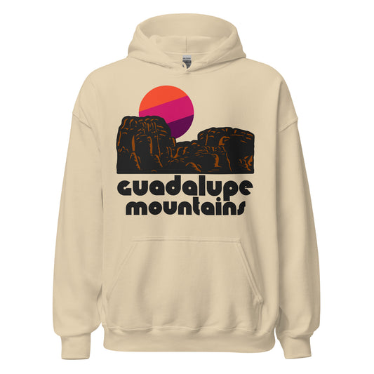 A sand colored vintage hoodie sweatshirt that says "Guadalupe Mountains" in Texas and includes an image of brown desert and mountain landscape and an orange, pink, and purple sun.