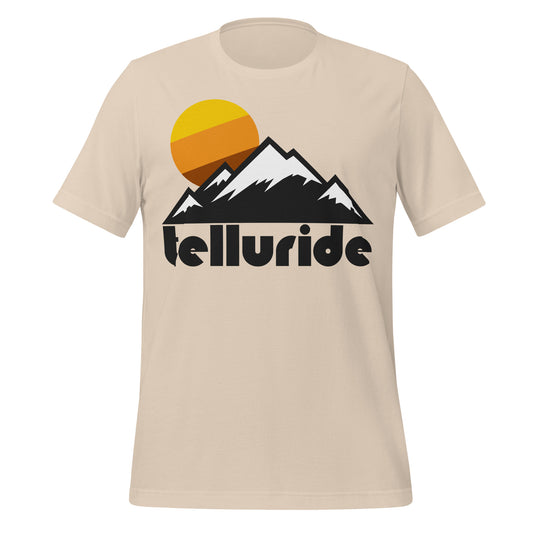 An 80s style sand colored “Telluride” t-shirt with the image of a mountainous landscape, complete with snowy peaks, and an orange/brown/yellow sun setting. References Telluride Ski Resort which is tucked away in the San Juan Mountains, which is part of the Rocky Mountain Range, known for being the area with the highest concentration of 13,000 and 14,000 foot mountains in North America.