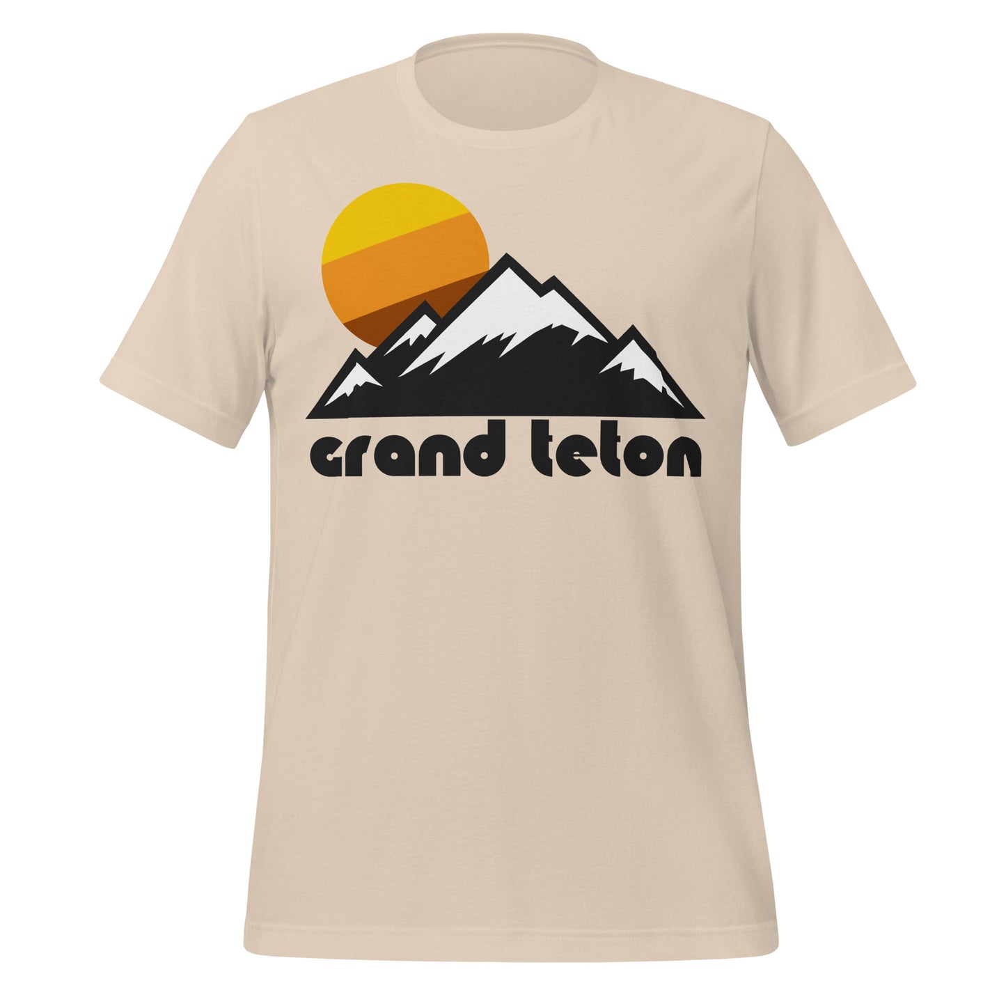 A soft cream colored 80s style "Grand Teton" t-shirt, referencing the mountain range as part of the Grand Teton National Park in Wyoming, right next to Yellowstone. The shirt includes the image of a snowy mountain landscape and a yellow, orange, and brown sun setting.
