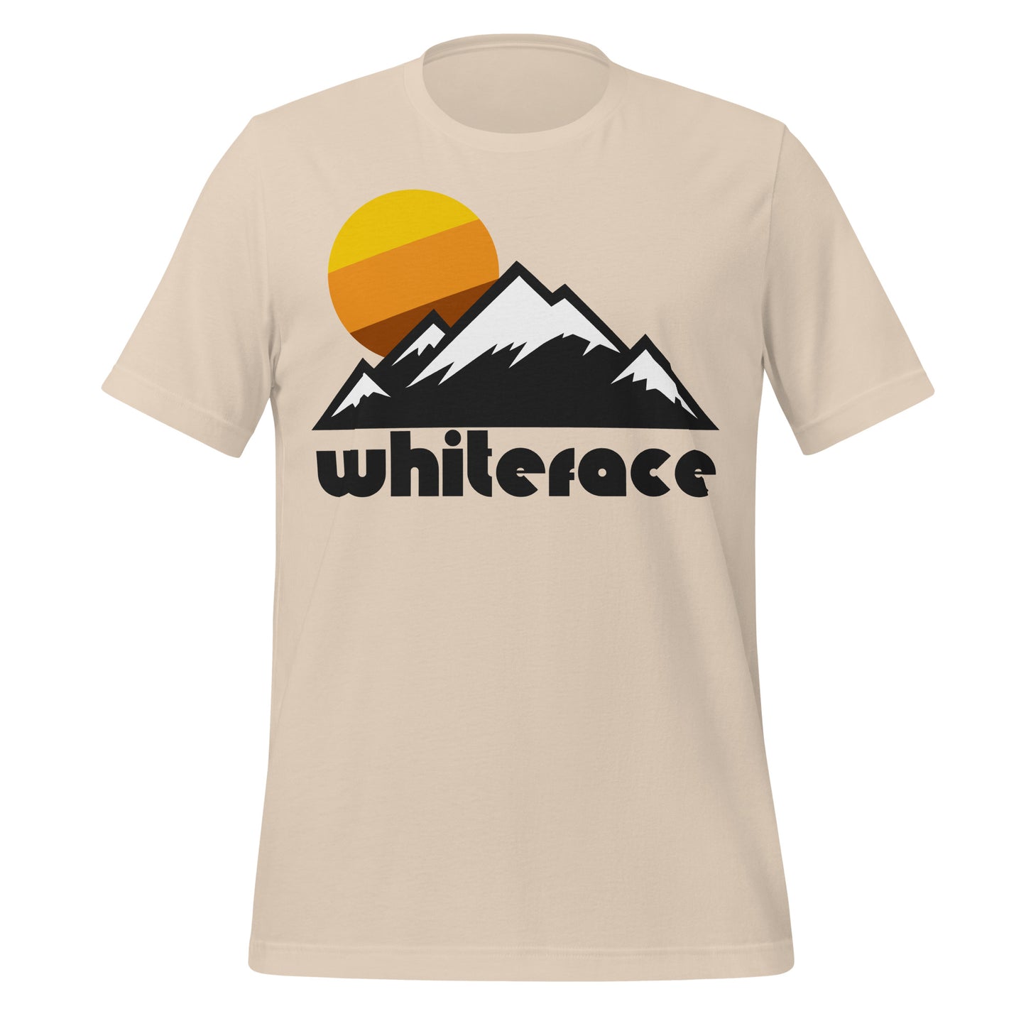 A soft cream colored 70s style t-shirt that says "Whiteface", referencing Whiteface Mountain, the 5th highest mountain in New York and part of the Adirondack Mountains, and home to the New York Ski resort. The vintage t-shirt includes images of multiple snowcapped mountain peaks and a tricolored yellow/orange/brown sun setting.