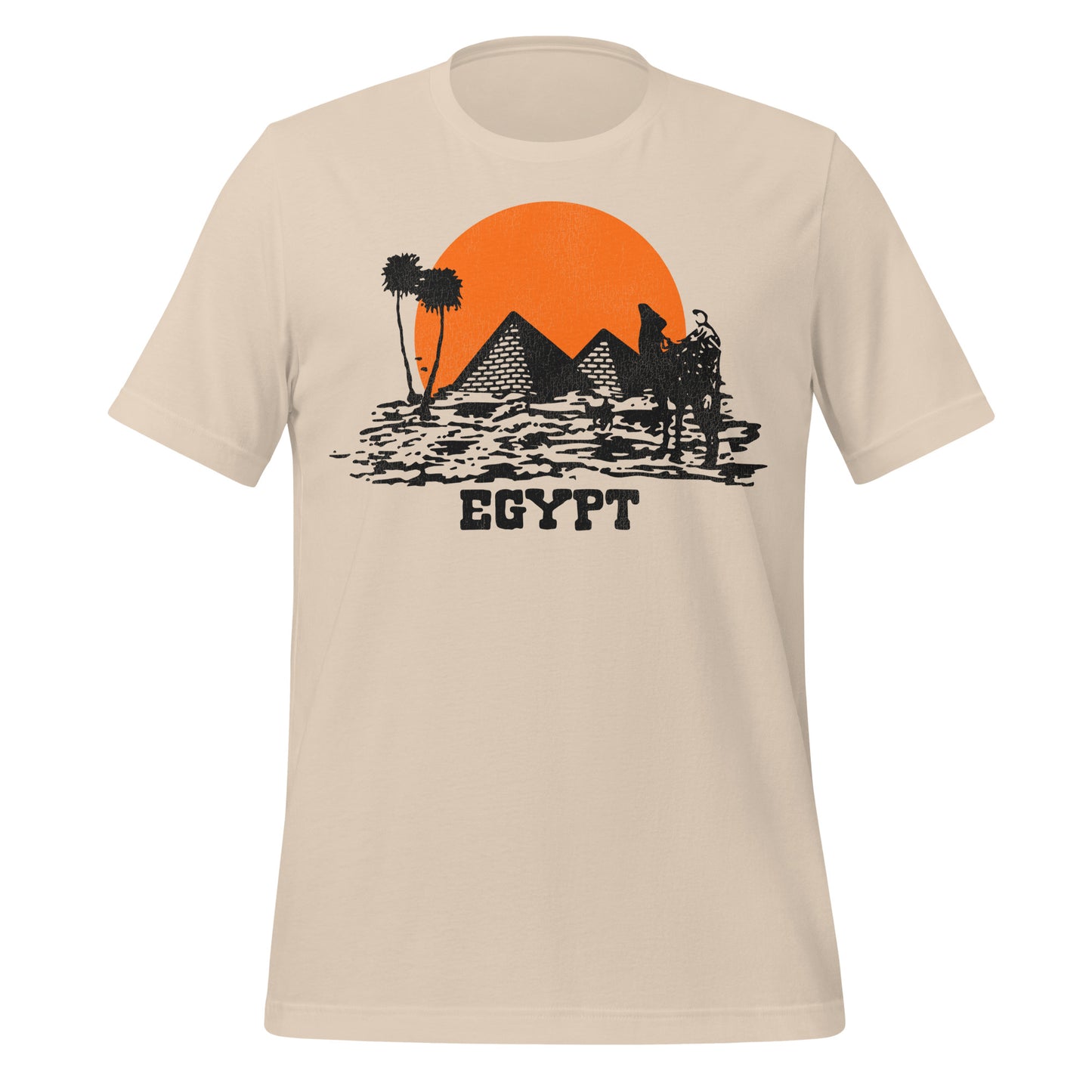 A soft cream colored retro Egypt t-shirt with an image of an orange sun setting behind the pyramids, palm trees and a camel in the distance on top of the desert.
