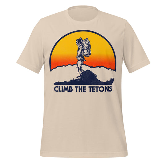 A soft cream retro 70s style t-shirt that says "Climb the Tetons". References the Grand Tetons, a mountain range and national park near Jackson, Wyoming and next to Yellowstone National Park. Image of a yellow and red hombre sun behind a person hiking at the top of the range, wearing backpacking gear.