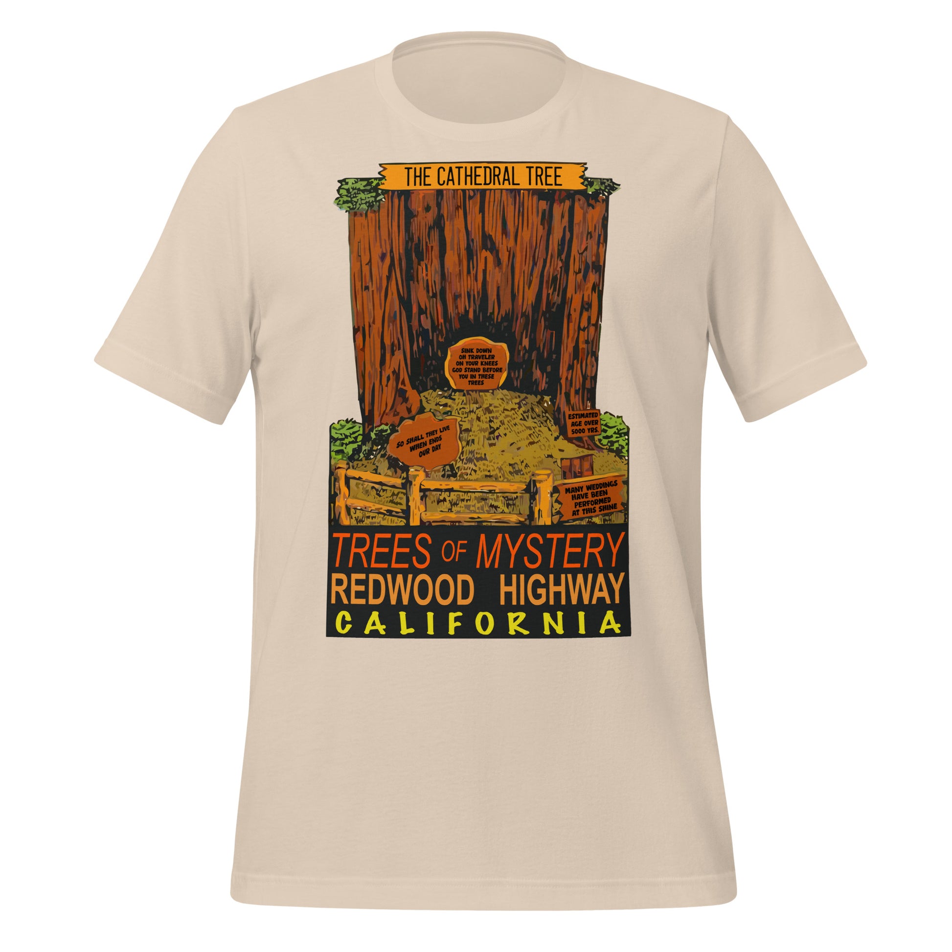 A 70s style soft cream t-shirt with an image of "The Cathedral Tree", a hollowed out redwood behind a wooden fence with many signs saying "Estimated Age Over 500 Years", "Sink Down, Oh Traveler, On Your Knees, God Stand Before You In These Trees", "Many Weddings Have Been Performed At This Site", and "So Shall They Live When Ends Our Day". T-shirt also says "Trees of Mystery", located on the "Redwood Highway" in "California" in orange, red, and yellow colors.