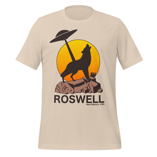 A retro 80s style t-shirt that says Roswell New Mexico, USA with the image of a wolf in shadow on top of brown rocky land, a UFO in the distance shining it's light straight down in front of a rising orange and yellow sun. In reference to the alien UFO Incident which served as a catalyst for America's UFO obsession.
