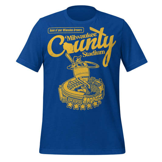 A bright royal blue vintage t-shirt that says "Milwaukee County Stadium" with an image of Wisconsin for the "O" in "County". Says "Home of your Milwaukee Brewers". Image of a baseball player with a bat on top of a baseball stadium with five stars in yellow and blue, the colors of the Milwaukee Brewers.
