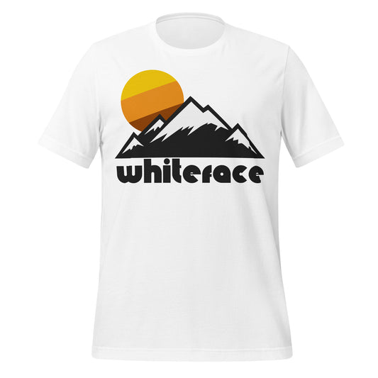 A white colored Whiteface Mountain tourist t-shirt with the image of multiple mountains, covered in snow, and a sun. References Whiteface Mountain, one of the High Peaks of the Adirondacks, home to the 1980s Winter Olympics alpine skiing competition, and a famous skiing mountain today including the New York Ski Resort.