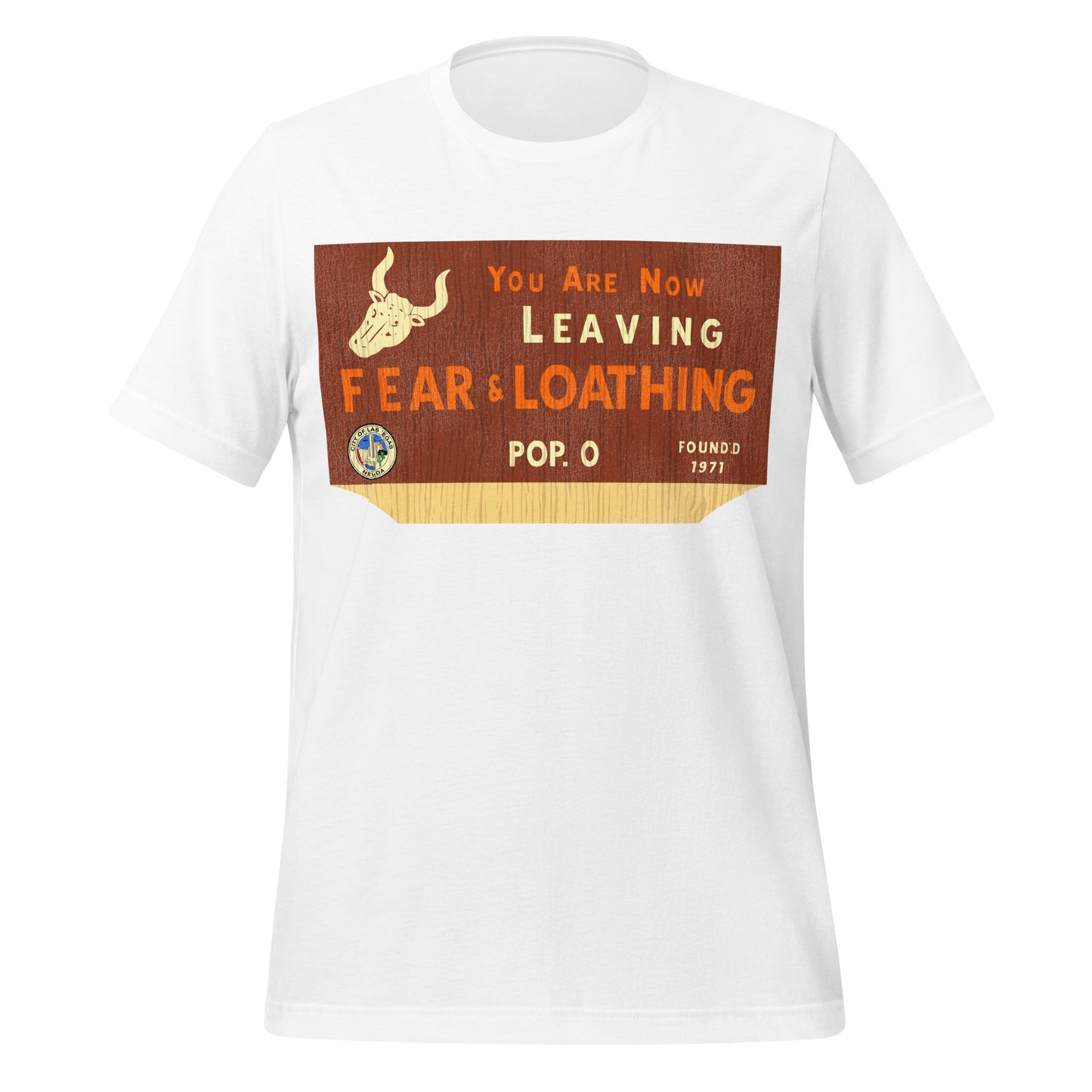 A white, vintage t-shirt that says "You are Now Leaving Fear & Loathing", "Pop. 0" (or population 0), "Founded 1971", and the Seal of Las Vegas, Nevada (which says 'City of Las Vegas, Nevada' with buildings, sun, desert, and a cactus in the center). Image of a bison with two horns on a wooden background. References the iconic American film 'Fear and Loathing in Las Vegas'.
