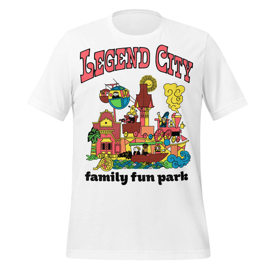 An 80s style vintage t-shirt that says "Legend City", "family fun park" in reference to the closed theme park near Tempe and Pheonix, Arizona. Images of people riding amusement park rides including trains, boats, & skyways. Images of pink, yellow, and red buildings, blue swirling waves, and a fake cannon going "boom".