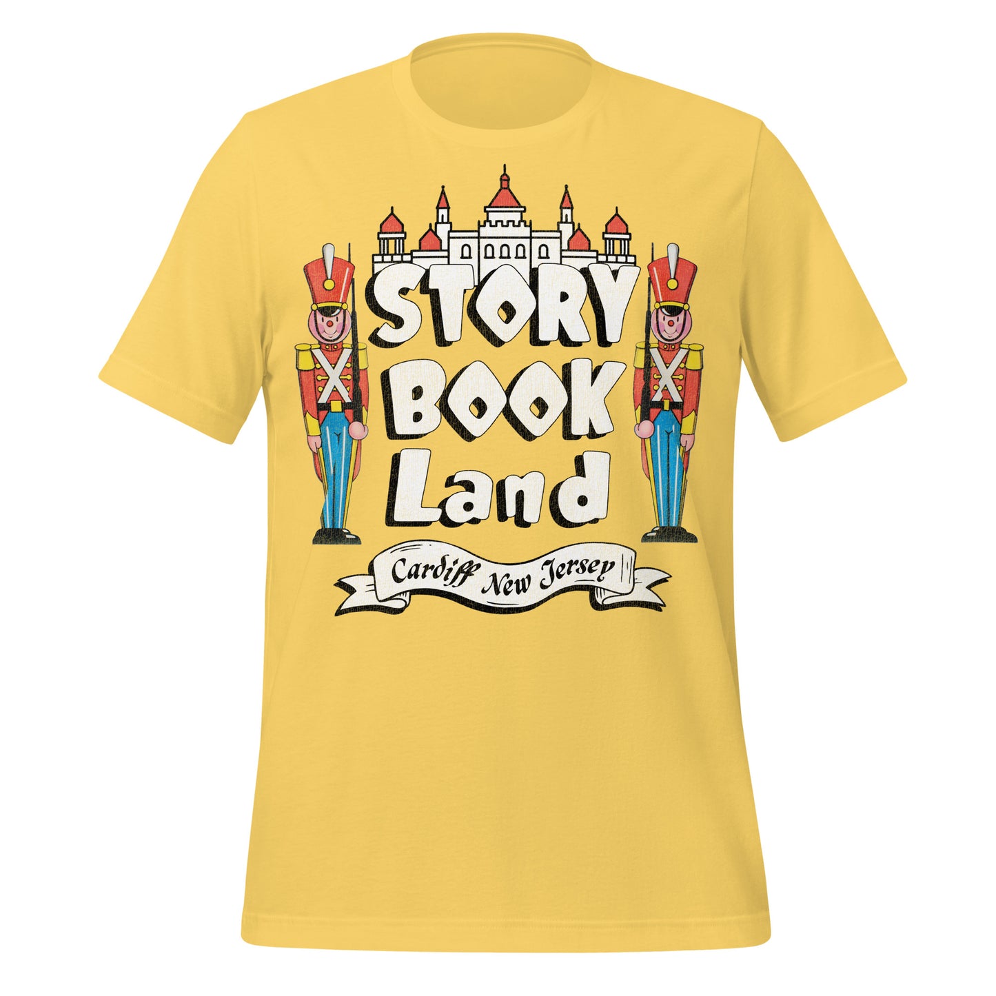 A bright yellow tourist t-shirt that says Story Book Land in white bubble letters and "Cardiff New Jersey" referring to the amusement park. Has two toy soldiers resembling the Nutcracker and London palace guards and a castle.