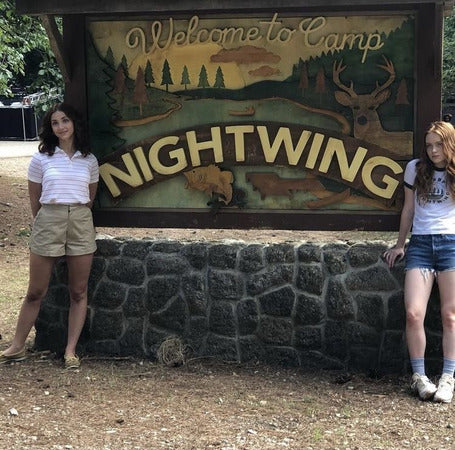 two girls standing in front of a welcome sign
