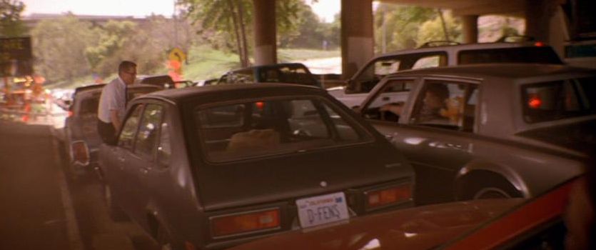 a busy parking lot with several cars parked under a bridge, and a person standing near one of the cars.