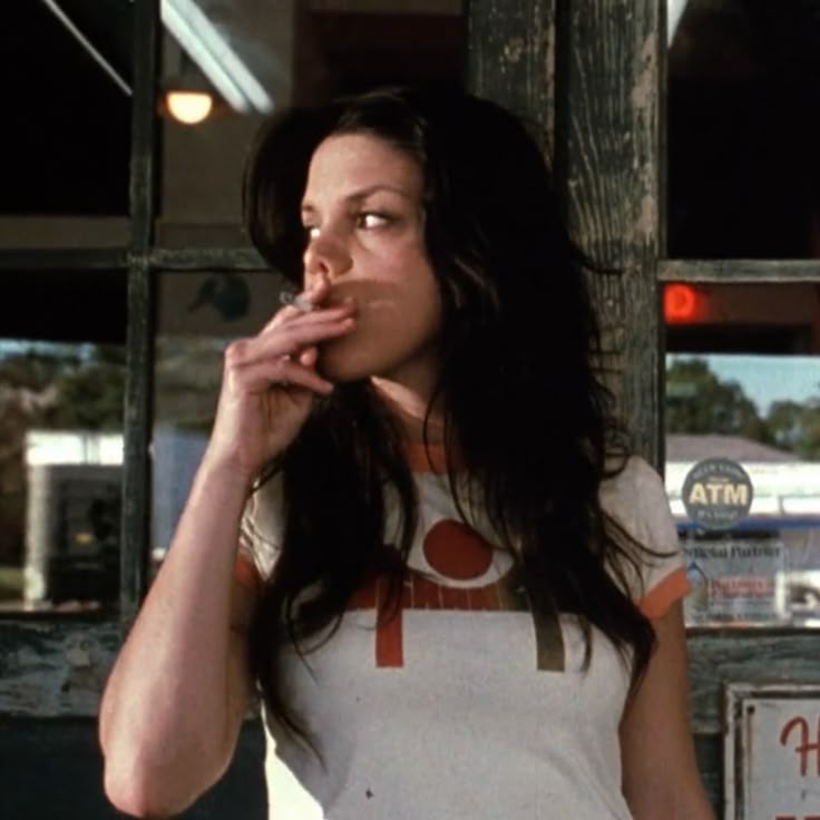a woman smoking a cigarette in front of a store
