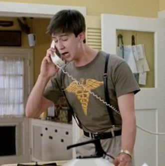 a man talking on a phone in a kitchen
