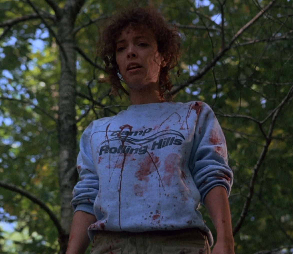 a young woman standing in front of a tree holding a frisbee