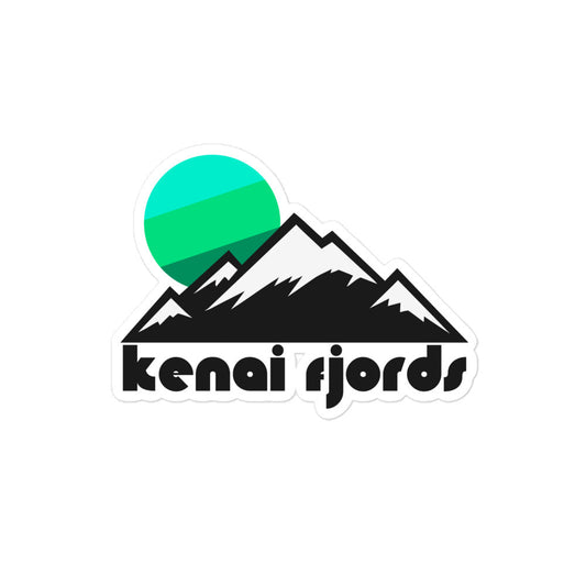 A retro, vintage kiss cut sticker with a beautiful snow covered mountain landscape and a bright sun setting in blue and green colors. Says 'kenai fjords', referencing Kenai Fjords National Park in Kenai Peninsula Borough, Alaska, known for its stunning coastal fjords, islands, and glaciers, as well as Harding Icefield, near the town of Seward. 