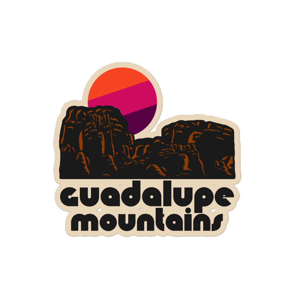 A retro kiss cut sticker that says Guadalupe Mountains under a red rock landscape with an orange, pink, and purple setting sun. References the national park in Texas. 