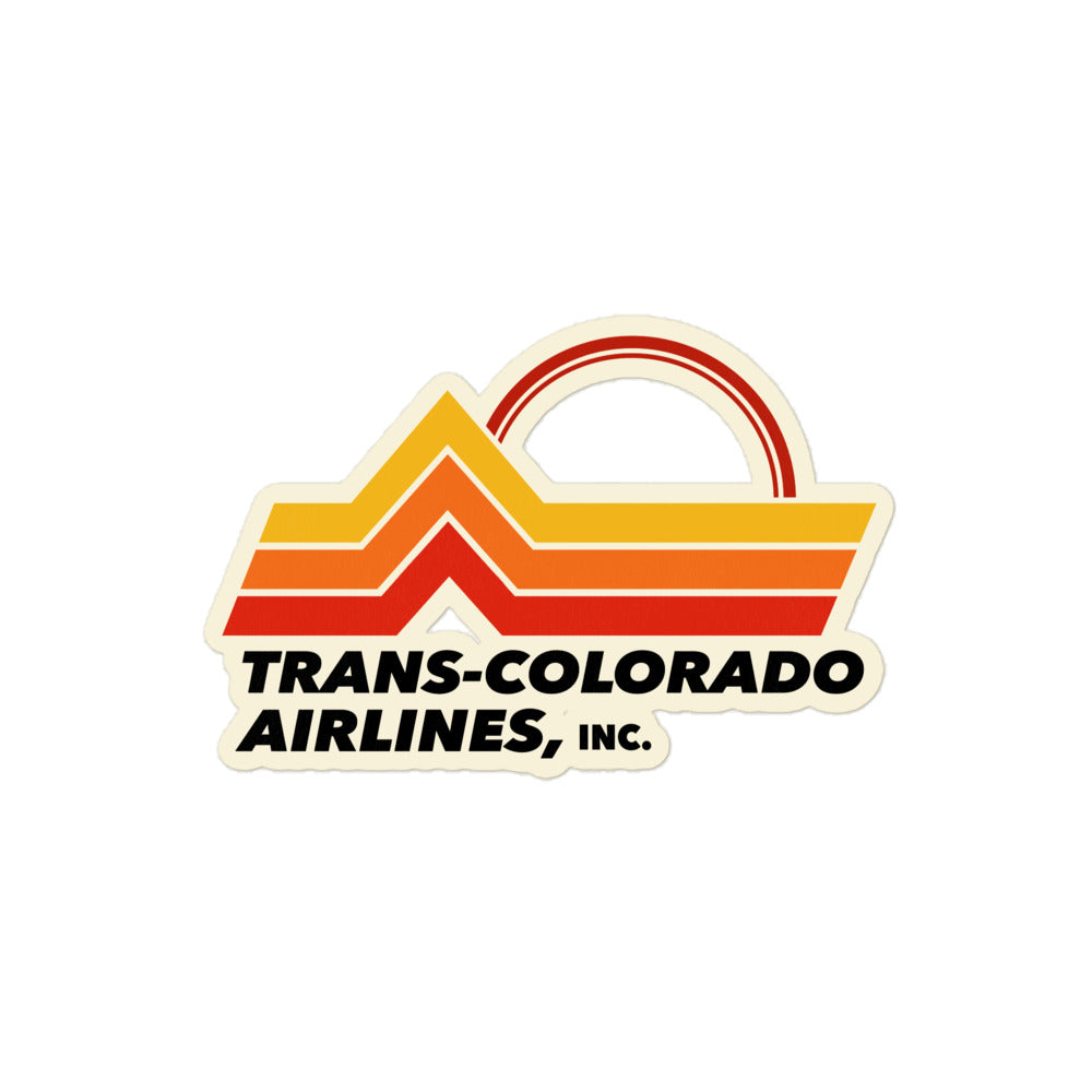 A kiss cut sticker saying "Trans-Colorado Airlines, Inc." with the image of yellow, orange, and red mountain landscape and a  setting sun. 