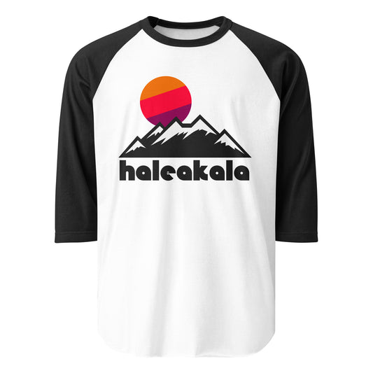 A black and white three quarter sleeve vintage raglan style shirt with the image of a mountain range, its peaks snow covered, and a bright orange, purple, and red sun setting, representative of the stunning sunsets seen from Haleakalā Volcano. The shirt references Haleakalā National Park on the island of Maui, Hawaii, known for its picturesque night skies, hikes to the volcano crater, and beautiful views. 