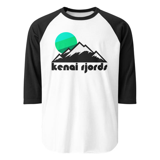 A retro black and white raglan style shirt that reads "Kenai Fjords" under the image of a snowy mountain range, a blue and green tricolor sun setting over the snowy peaks. In reference to Kenai Fjords National Park near Seward, Alaska, an area known for its stunning glaciers flowing out of the Harding Icefield, looking like the ice age. 